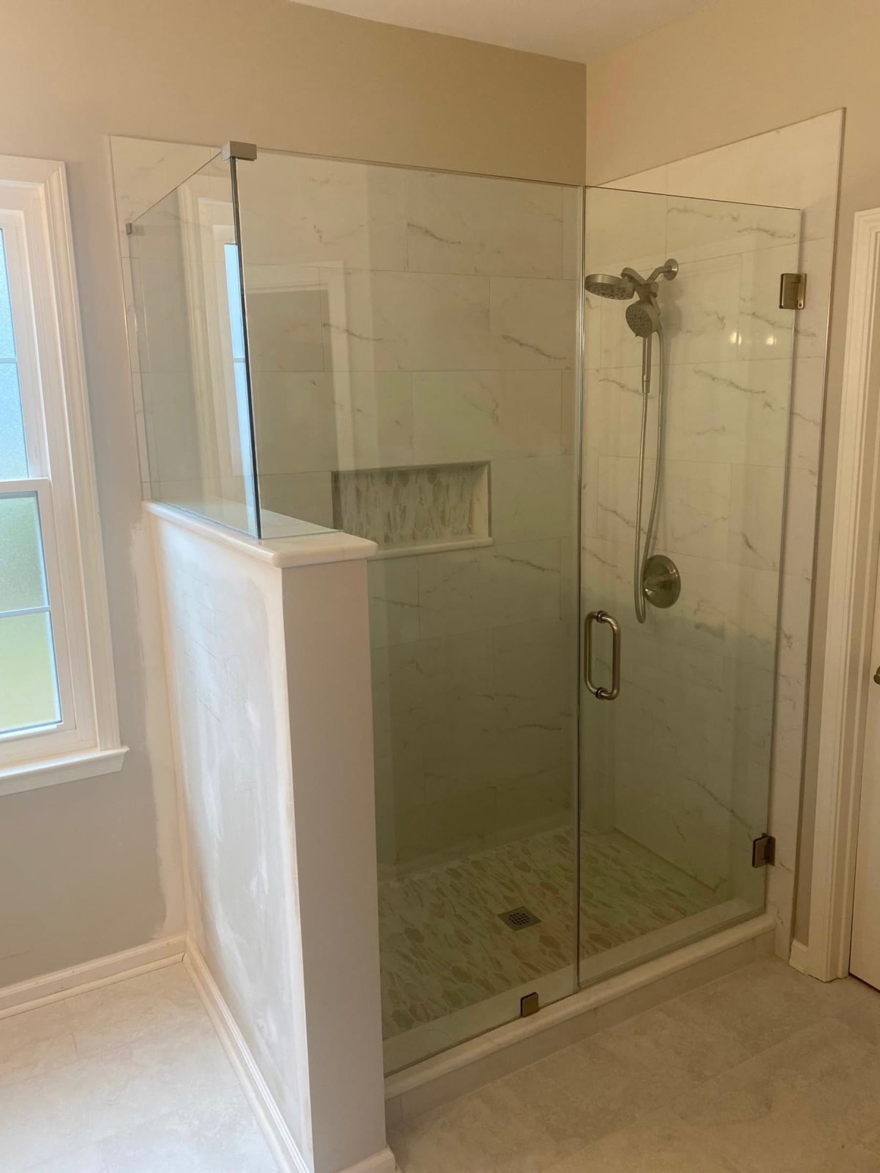 Frameless glass shower enclosure with marble tile by DgGlass